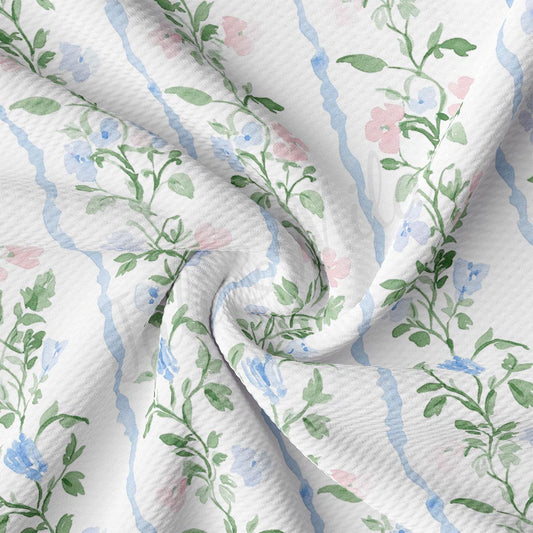 a close-up view of a fabric with a floral pattern, featuring green and pink flowers and leaves. The fabric appears to be crumpled and wrinkled, giving it a soft and delicate appearance.