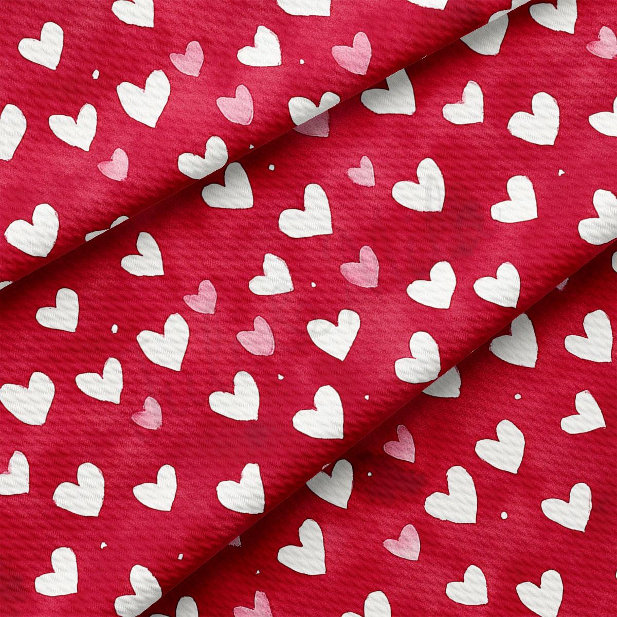 a close-up view of a red fabric with white hearts printed on it. The hearts are arranged in a repeating pattern, creating a visually striking and symmetrical design.