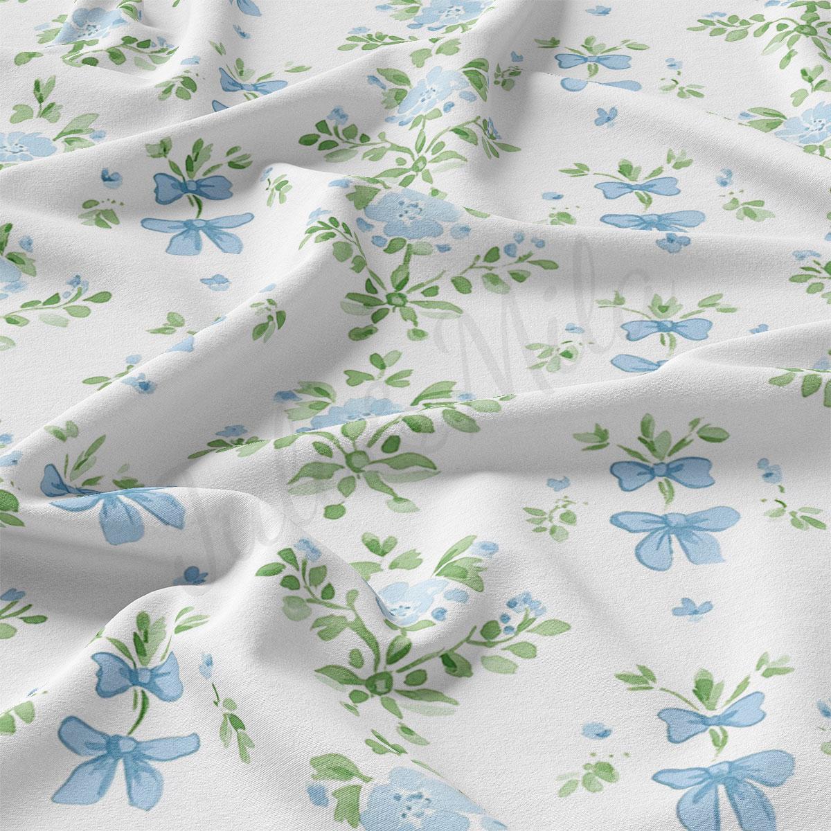 a close-up view of a fabric with a floral pattern of blue flowers and green leaves. The fabric appears to be crumpled, giving it a soft and delicate appearance.