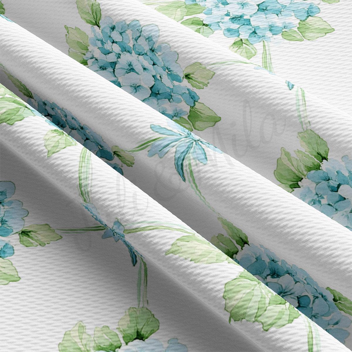 a close-up view of a fabric with a floral pattern of blue and green flowers. The fabric appears to be white, and the pattern is intricate and detailed, with the flowers and leaves overlapping each other in a visually appealing manner.