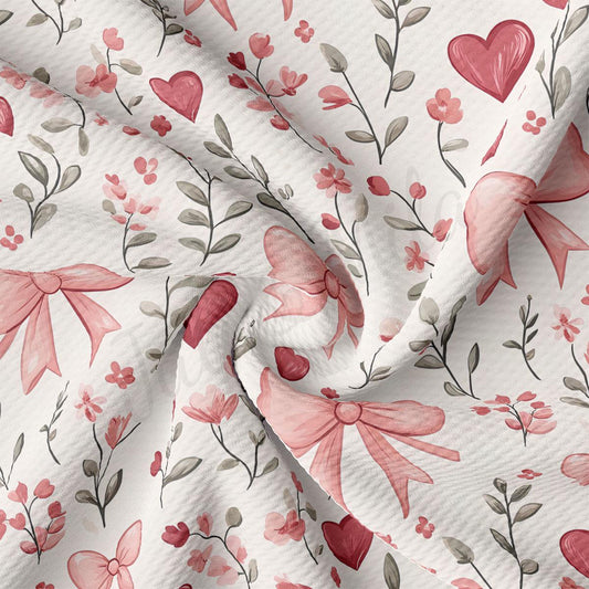 a close-up view of a fabric with a floral pattern. The pattern consists of pink flowers, leaves, and bows, creating a visually appealing and delicate design.