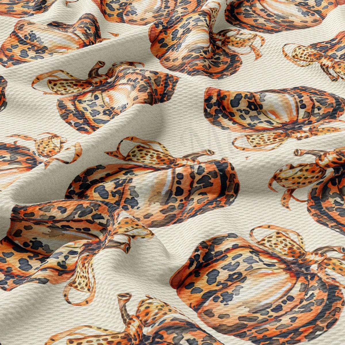 a close-up view of a fabric with a repeating pattern of leopard-like animals, including giraffes and snakes, in shades of orange and black.