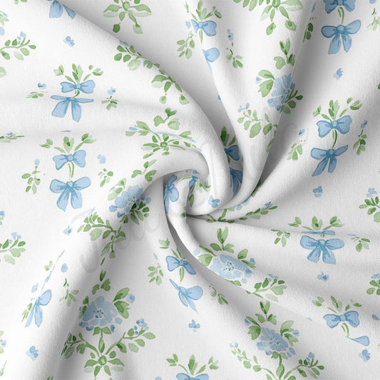 a close-up view of a fabric with a floral pattern of blue flowers and green leaves. The fabric appears to be white and has a crinkled texture, giving it a soft and delicate appearance.