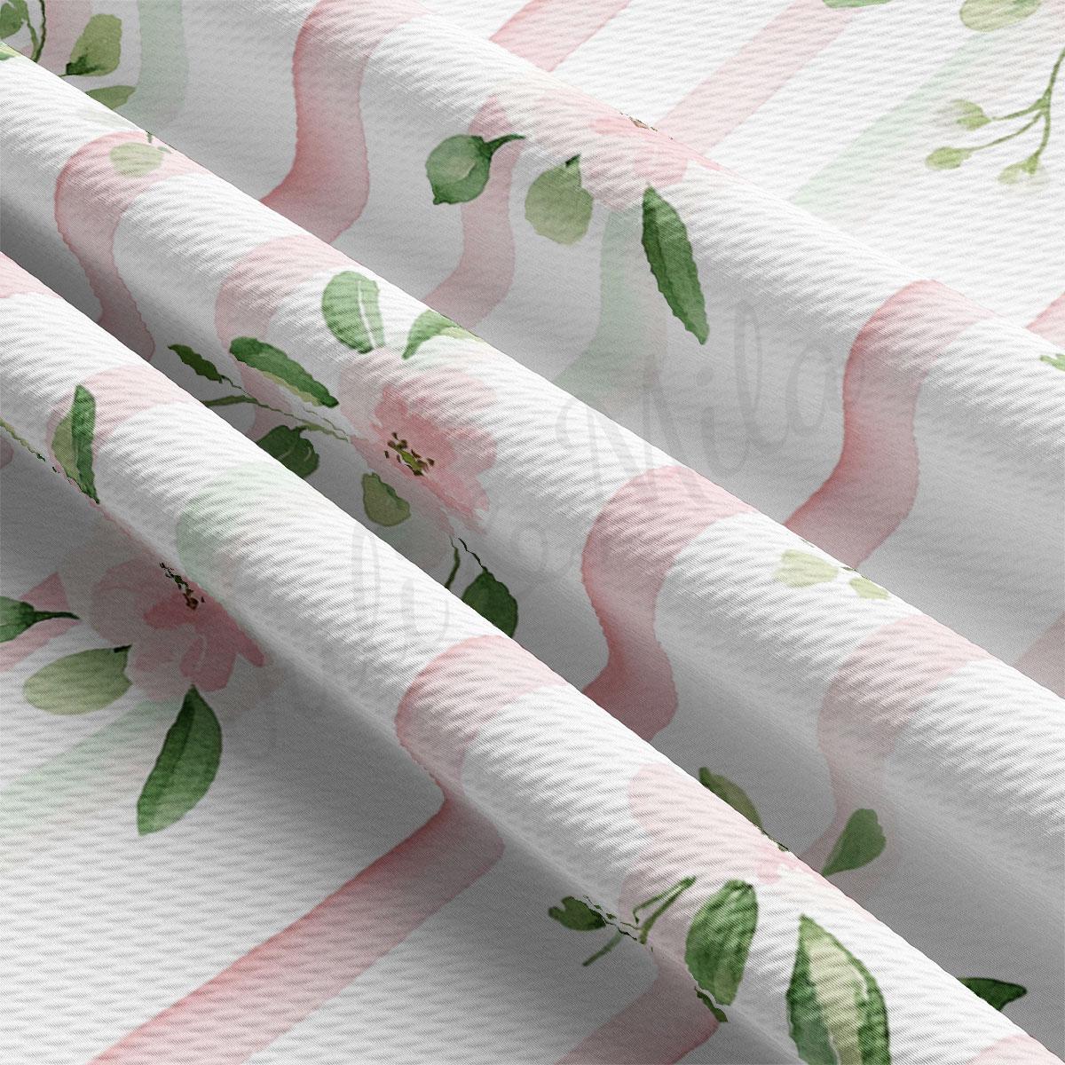a close-up view of a fabric with a floral pattern, featuring pink and green leaves and flowers. The fabric appears to be made of a soft, textured material, possibly cotton or linen.