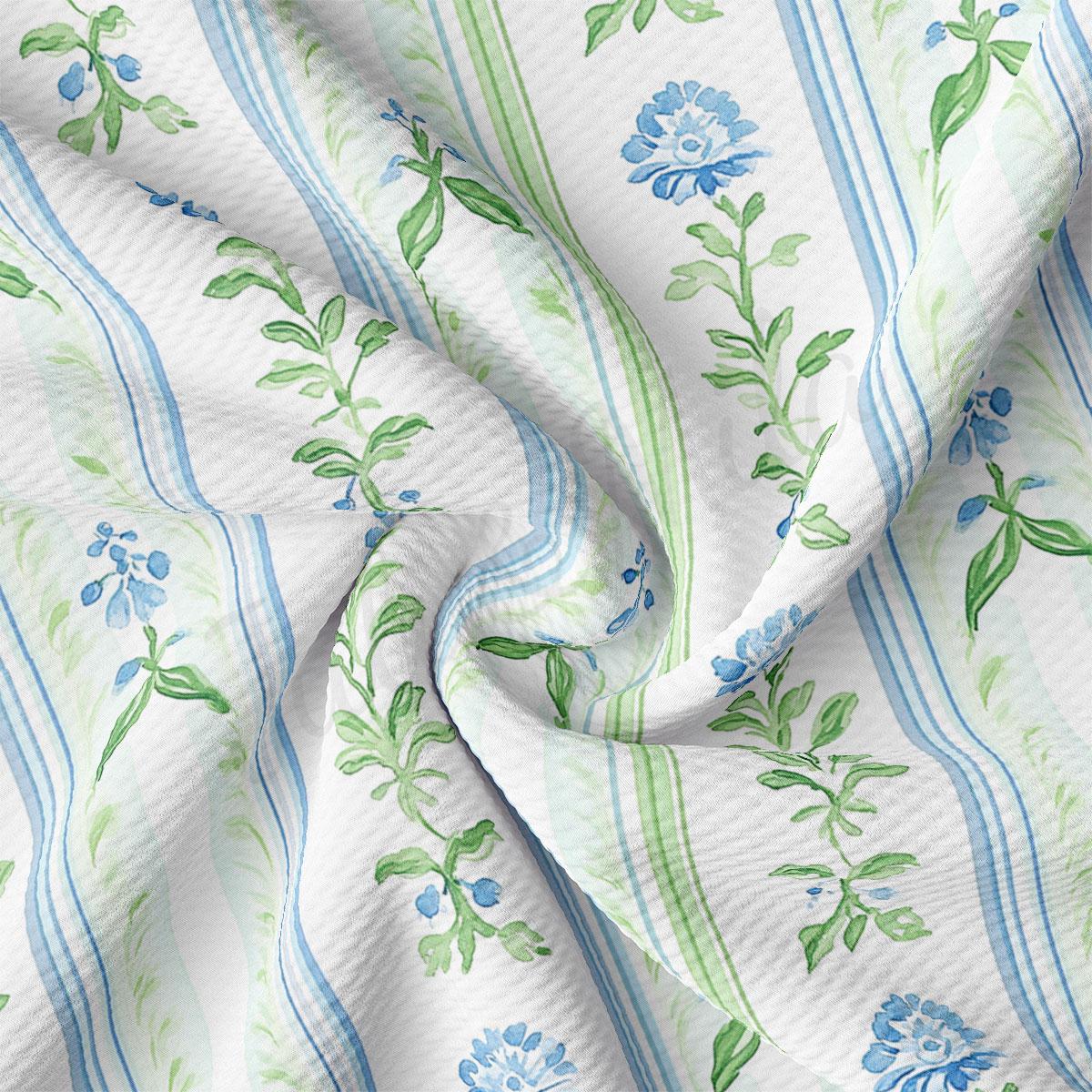 a close-up view of a fabric with a floral pattern, featuring blue and green leaves and flowers. The fabric appears to be crumpled and wrinkled, giving it a soft and delicate appearance.