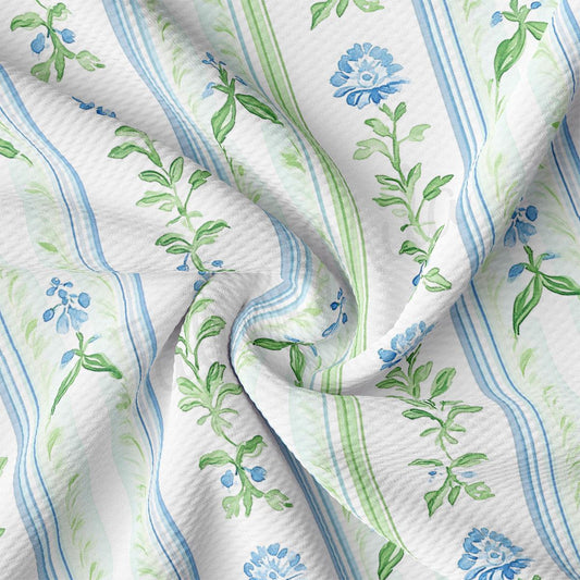 a close-up view of a fabric with a floral pattern, featuring blue and green leaves and flowers. The fabric appears to be crumpled and wrinkled, giving it a soft and delicate appearance.