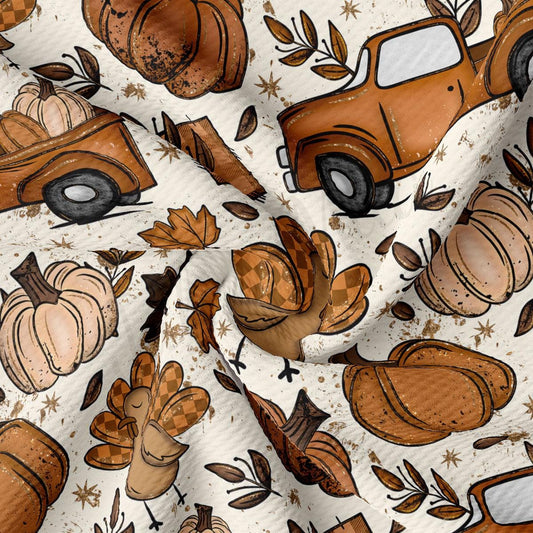 The image is a close-up of a fabric with a repeating pattern of autumn-themed illustrations, including pumpkins, turkeys, and a truck.