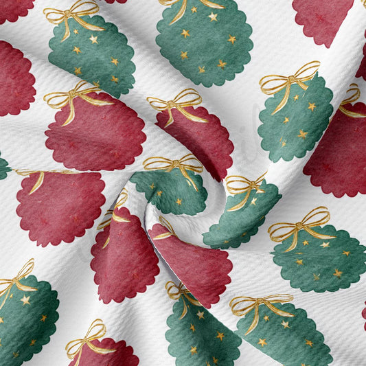 a close-up view of a fabric with a repeating pattern of Christmas-themed designs, including green and red Christmas trees with gold bows and stars.