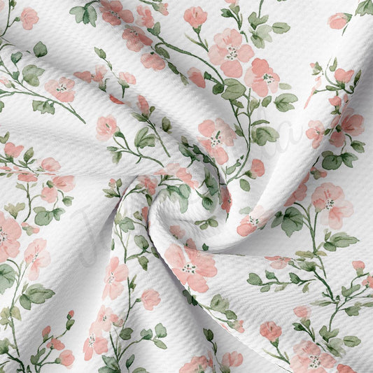 a close-up view of a fabric with a floral pattern of pink flowers and green leaves. The fabric appears to be white and has a textured appearance.