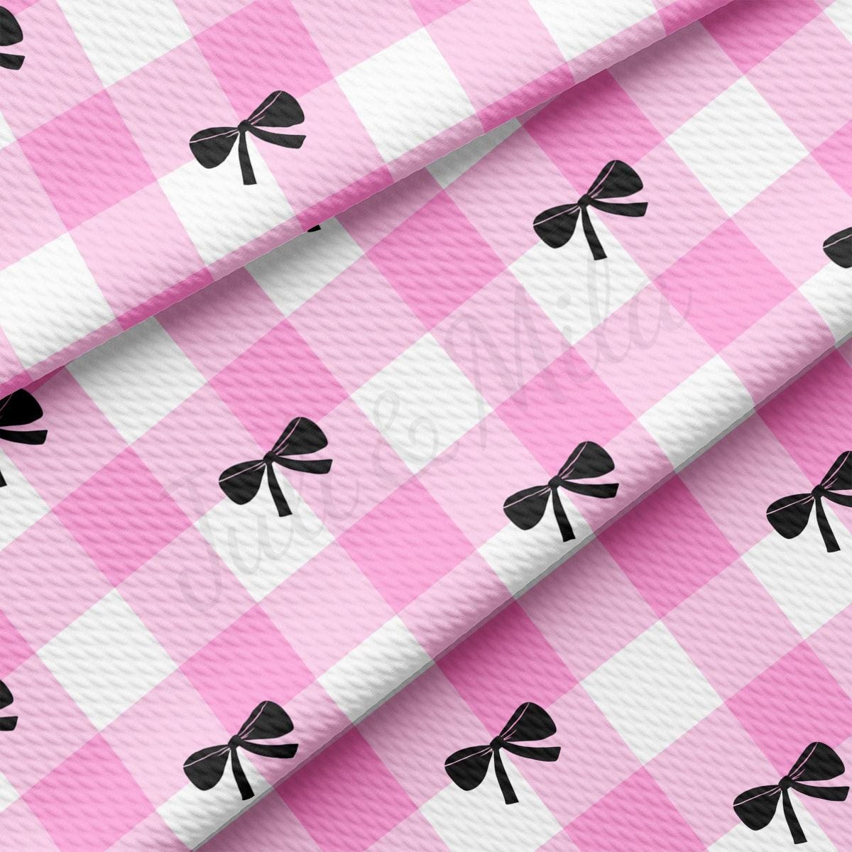 a pink and white checkered table cloth with a black bow on it