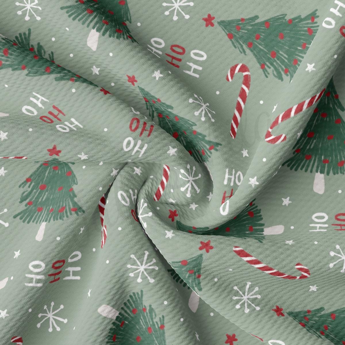 a green fabric with christmas trees and candy canes